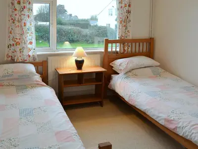 two twin beds in a room with a window at Chynoweth in Saint Keverne