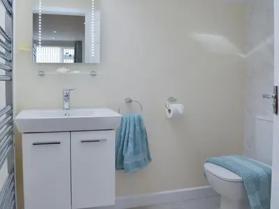 a white bathroom with a sink and a toilet at Driftwood in Port Isaac