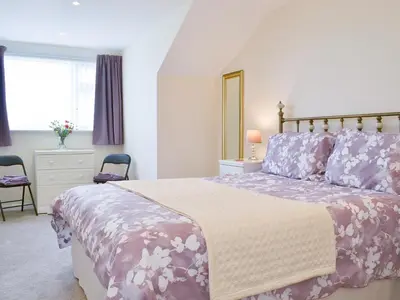 a bedroom with a large bed with purple and white sheets at Driftwood in Port Isaac
