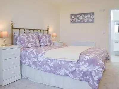 a bed with a purple comforter and a night stand at Driftwood in Port Isaac