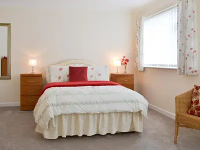 a bedroom with a bed and two dressers and a window at Driftwood in Port Isaac