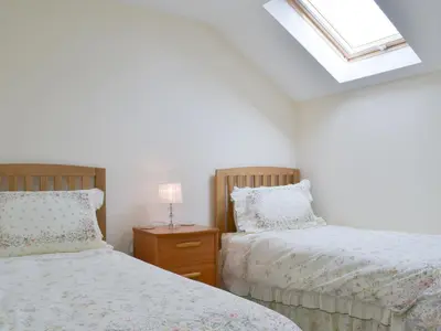 a bedroom with two beds and a skylight at Driftwood in Port Isaac