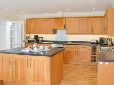 a kitchen with wooden cabinets and a black counter top at Driftwood in Port Isaac