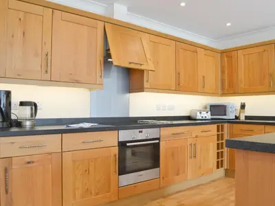 a kitchen with wooden cabinets and black counter tops at Driftwood in Port Isaac