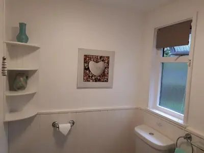 a bathroom with a toilet and a heart picture on the wall at Woodland Retreat in Uny Lelant