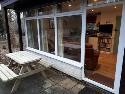 a screened in porch with a bench and a table at Woodland Retreat in Uny Lelant
