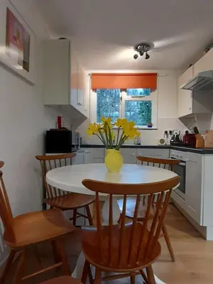 a kitchen with a table with a vase of flowers on it at Woodland Retreat in Uny Lelant