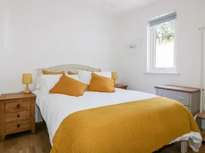 a bedroom with a large bed with a yellow blanket at Avalon in St. Agnes