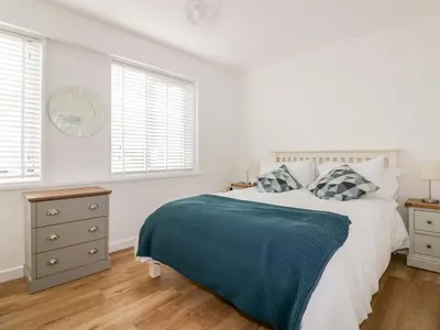 a white bedroom with a bed and two windows at Avalon in St. Agnes