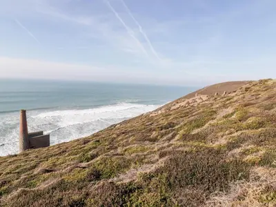 a grassy hill with the ocean in the background at Avalon in St. Agnes