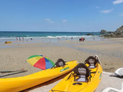 two yellow kayaks on a beach with people in the ocean at Avalon in St. Agnes