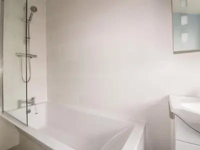 a white bathroom with a tub and a sink at Avalon in St. Agnes