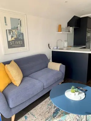a living room with a blue couch and a table at Modern studio apartment with stunning views! in St Ives