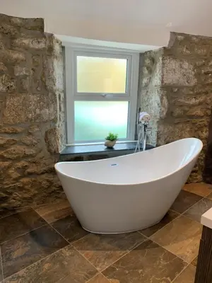 a white bath tub in a bathroom with a window at Modern studio apartment with stunning views! in St Ives