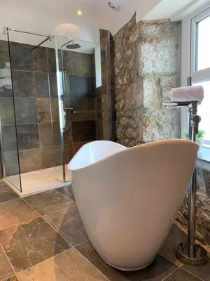 a bath tub in a bathroom with a glass shower at Modern studio apartment with stunning views! in St Ives