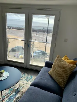 a living room with a couch and a view of the beach at Modern studio apartment with stunning views! in St Ives