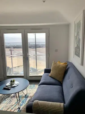 a living room with a blue couch and a table at Modern studio apartment with stunning views! in St Ives