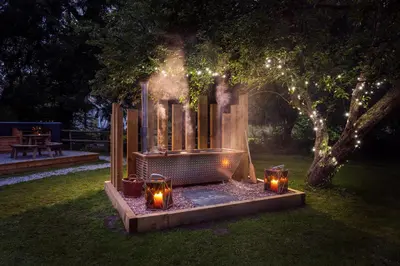 a fire pit in a yard with candles and lights at The Wriggly Tin & Baa Spa at Tregoose Old Mill in Newquay