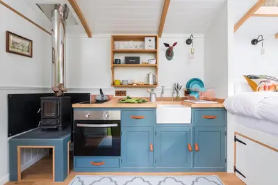 a small kitchen with blue cabinets and a sink at The Wriggly Tin & Baa Spa at Tregoose Old Mill in Newquay