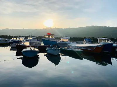 a group of boats docked in the water at sunset at Truly Paradise Cottage in Golant