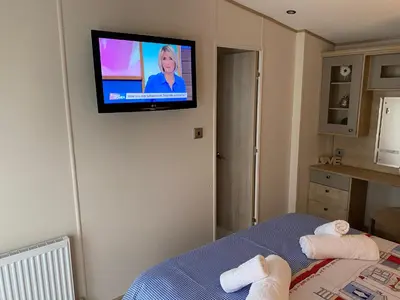 a room with a tv on a wall with towels on a bed at Valley View with a luxurious hot tub in Newquay