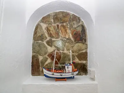 a small boat sitting on a shelf next to a stone wall at Trevena Lodge in Tintagel