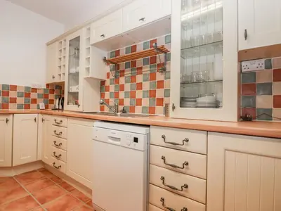 a kitchen with white cabinets and a dishwasher at Trevena Lodge in Tintagel