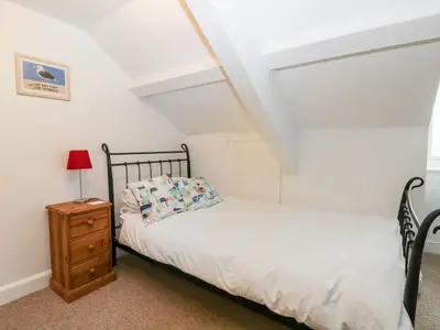 a bedroom with a bed and a wooden nightstand at Trevena Lodge in Tintagel
