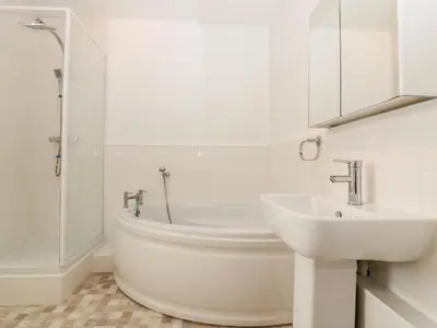 a white bathroom with a tub and a sink at Trevena Lodge in Tintagel