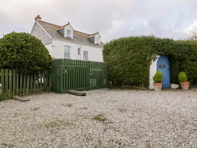 a white house with a fence and a yard at Trevena Lodge in Tintagel