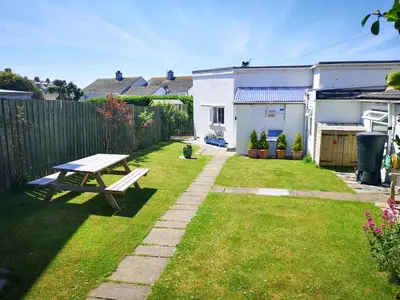 a backyard with a picnic table in the grass at Gull Cottage in Tintagel