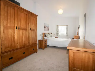 a bedroom with a bed and a large wooden cabinet at Gull Cottage in Tintagel