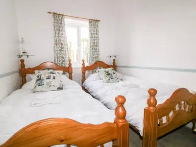 two twin beds in a bedroom with a window at Gull Cottage in Tintagel
