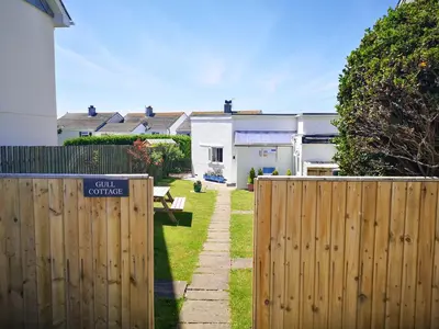 a fence in front of a yard with a house at Gull Cottage in Tintagel