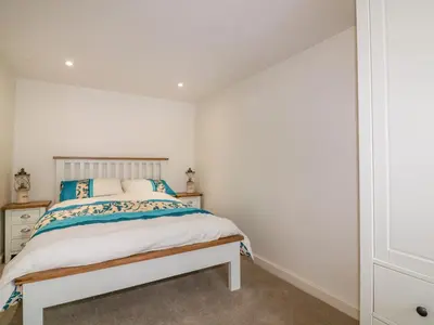 a bedroom with a bed and a white wall at Cove Cottage in Tintagel
