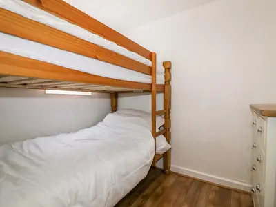 a bedroom with two bunk beds and a desk at Cove Cottage in Tintagel
