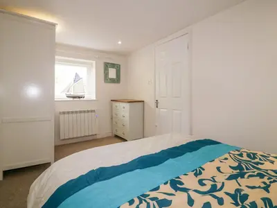 a bedroom with a bed and a window with a sailboat on it at Cove Cottage in Tintagel
