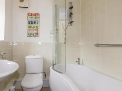 a bathroom with a toilet and a tub and a sink at Cove Cottage in Tintagel