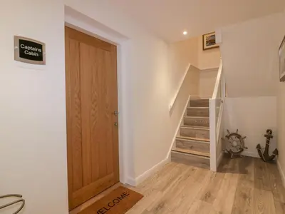 a hallway with a wooden door and stairs at Captain's Cabin in St Austell