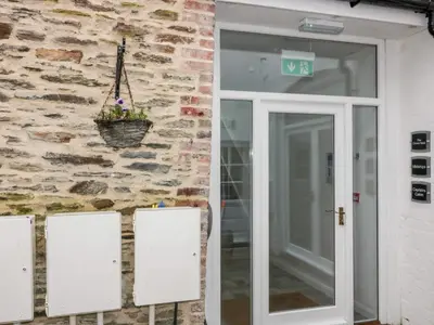a door to a building with a plant in a basket at Captain's Cabin in St Austell