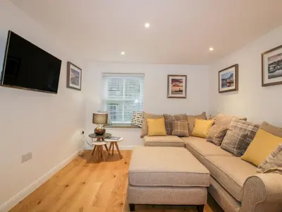 a living room with a couch and a flat screen tv at Captain's Cabin in St Austell