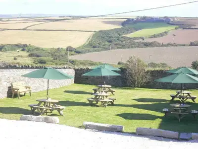 a group of picnic tables with umbrellas on the grass at Lellizzick Farmhouse in Padstow