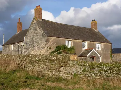 an old stone house with a stone wall at Lellizzick Farmhouse in Padstow