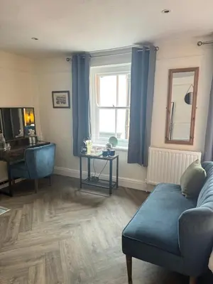 a living room with a blue couch and a window at The London Inn in Padstow