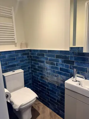 a blue tiled bathroom with a toilet and a sink at The London Inn in Padstow