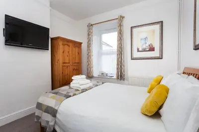 a bedroom with a white bed and a flat screen tv at The Olive Branch in St Ives