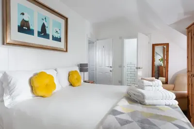 a bedroom with a white bed with yellow pillows at The Olive Branch in St Ives