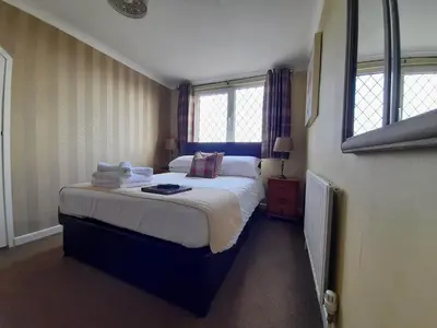 a bedroom with a large bed and two windows at Thurlestone House in St Ives