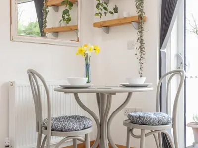 a table with two chairs and a vase with flowers at Chycoose in Truro