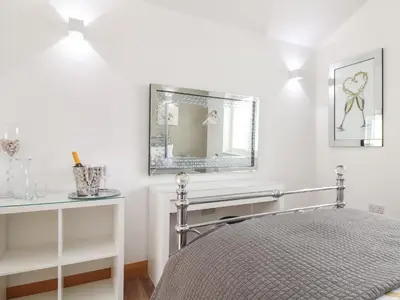 a white bedroom with a bed and a mirror at Chycoose in Truro